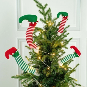 Close-up of plush Christmas elf legs with red and green stripes inside a decorated tree