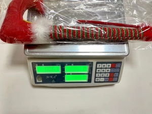 Elf leg Christmas tree decoration showing 63g weight on digital scale for logistics