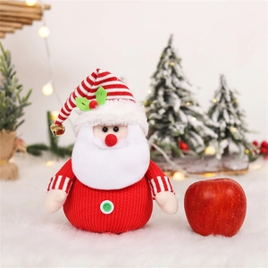 Knitted Santa plush toy with red stripe hat and bell next to a fresh apple