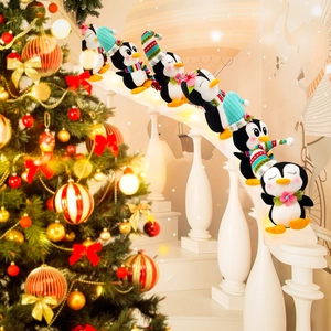 Set de pingüinos de peluche con gorros navideños y bufandas en una escalera de caracol