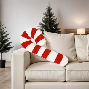 Close-up of candy cane plush pillow in red and white stripes on a sofa
