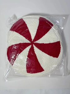 Close-up of red and white peppermint spiral plush pillow in clear plastic packaging