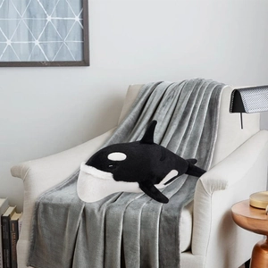 Detailed view of an orca plush toy on a white chair with a cozy grey flannel blanket