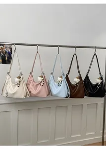 Close-up of hobo shoulder bags in five colors with plush charms and zip details
