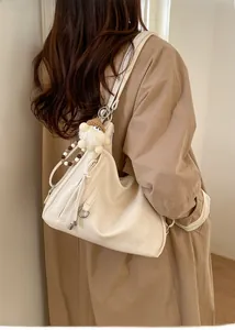 Detail of soft cream leather hobo bag with wooden beads and plush charm on a trench coat