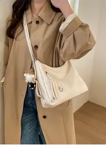 Detail of cream white Hobo shoulder bag with tassel knot and plush gnome pendant