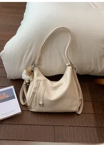 Detail of beige tote bag with pleated texture, front zippers and a cute sheep plush charm