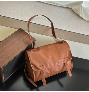 Detail of vintage caramel brown leather bag with elegant drape straps and metal hardware