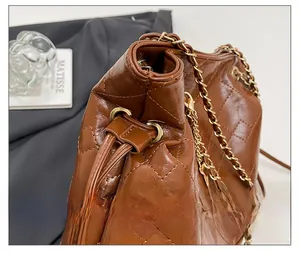 Detail showing the brown quilted leather bucket bag with a drawstring closure and gold chain