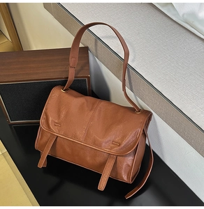 Close-up of brown vintage leather bag with pebble texture and decorative strap detail
