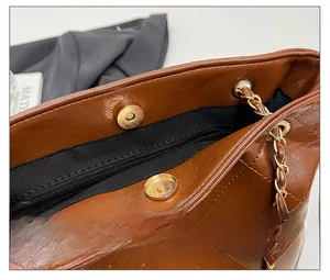 Detailed macro of brown quilted bucket bag with gold magnetic clasp and chain strap