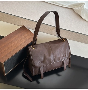 Detail view of deep brown soft faux leather shoulder bag with vintage gold metal buckles