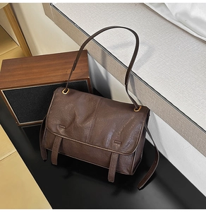 Detail of vintage dark brown faux leather bag with bronze buckles and worn texture