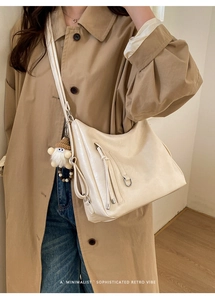 Off-white faux leather Hobo bag with fringe detail and plush charm on a casual model