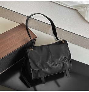 Detail view of the black leather bag with vintage gold hardware and wide shoulder strap