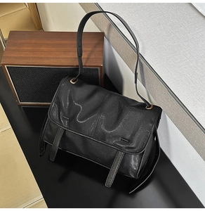 Detailed shot of vintage textured black leather messenger bag with matte gold hardware