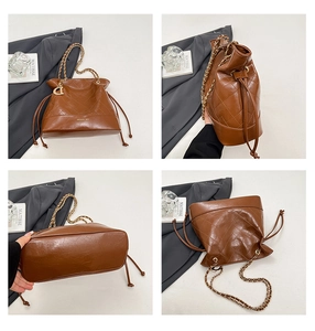 Detailed views of brown quilted leather bucket bag with gold chain and D pendant