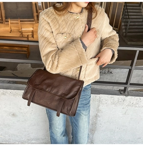 Detail of dark brown vintage faux leather shoulder bag worn with a faux fur coat