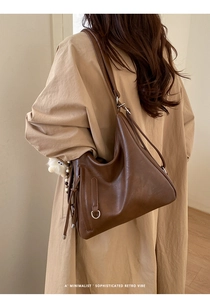 Close-up of minimalist brown retro tote bag with side metal rings and tassel details