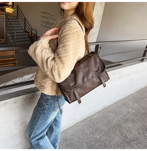 Close-up of a vintage dark brown messenger bag with decorative straps on a model