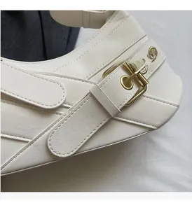 Macro shot of white lychee leather texture and golden metal buckle on shoulder bag