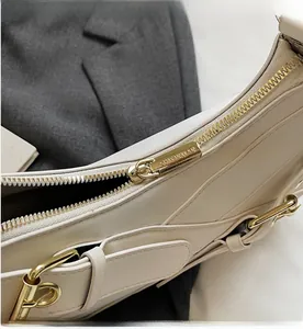 Close-up of light gold metal zipper detail with SHIYINMAN engraving on cream handbag