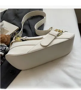 Detail of white leather shoulder bag with decorative buckles and gold-toned hardware