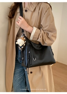 Detail of black faux leather shoulder bag featuring silver D-ring and plush pendant charm