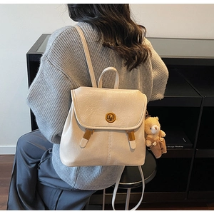 Detail of cream white PU leather backpack with vintage metal turn-lock and bear pendant