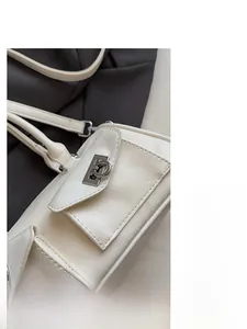 Detail of a creamy white leather shoulder bag featuring a silver twist-lock flap pocket