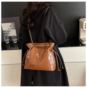Detail of caramel quilted bucket bag with gold chain strap and drawstring closure