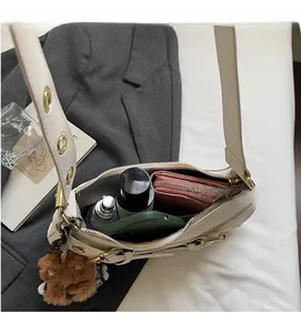 Detail view of the spacious cream baguette bag interior with smartphone and perfume