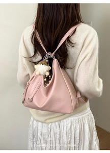 Pink PU leather crescent bag with silver hardware and plush charm shown on model back