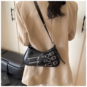Detail of black faux leather baguette bag with silver zippers and buckle accents