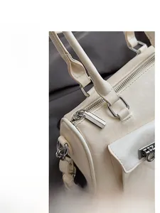 Detail of silver smooth zipper and metal buckle on off-white leather bowling bag