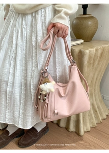 Pale pink matte leather tote detail featuring a cute plush doll charm and long strap