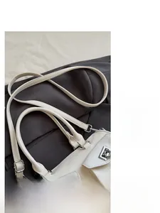 Detail of white PU leather baguette bag with silver hardware and adjustable straps