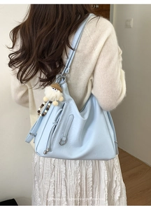 Detail of light blue retro tote bag with tassel decor and plush charm on a shoulder strap