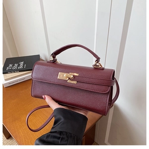 Détail d'un sac à main bordeaux en cuir grainé avec fermoir rotatif en métal doré