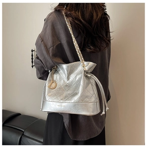 Detail of silver bucket bag with quilted pattern, drawstring and gold D charm