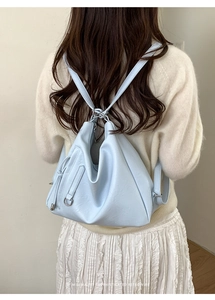 Close-up of light blue leather texture and metal rings on a minimalist retro backpack