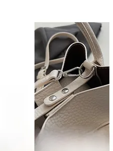 Macro view of silver hardware buckle and pebble grain leather on cream bucket bag