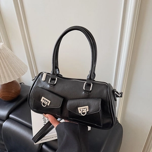 Detailed view of black barrel bag featuring silver metal buckles and dual front flap pockets