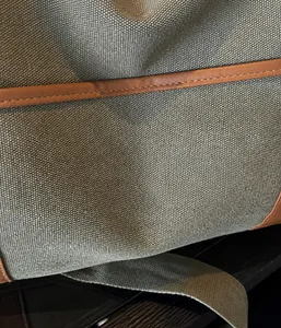 Detailansicht der graugrünen Canvas-Reisetasche mit braunem Lederbesatz und feinen Nähten