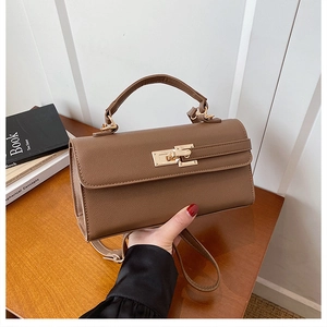 Détail d'un sac à main en cuir marron avec fermoir rotatif doré et poignée supérieure robuste