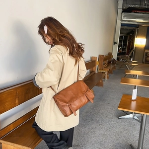 Retro brown messenger bag with a flap cover shown in a stylish outdoor cafe setting