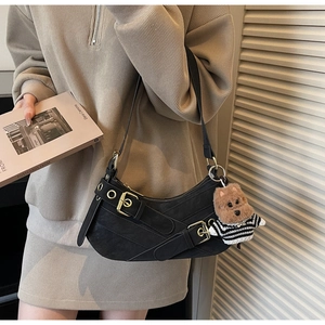 Detail of black leather hobo bag with metal buckles and cute teddy bear charm