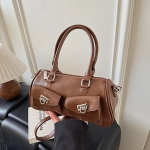 Detail of a brown leather cylindrical handbag with silver horseshoe buckles and pockets