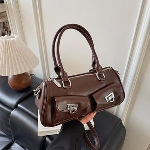 Detail of dark brown leather cylinder bag with utility pockets and adjustable strap