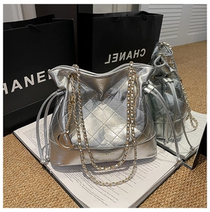 Macro shot of silver quilted bucket bag with gold chain strap and metal D pendant